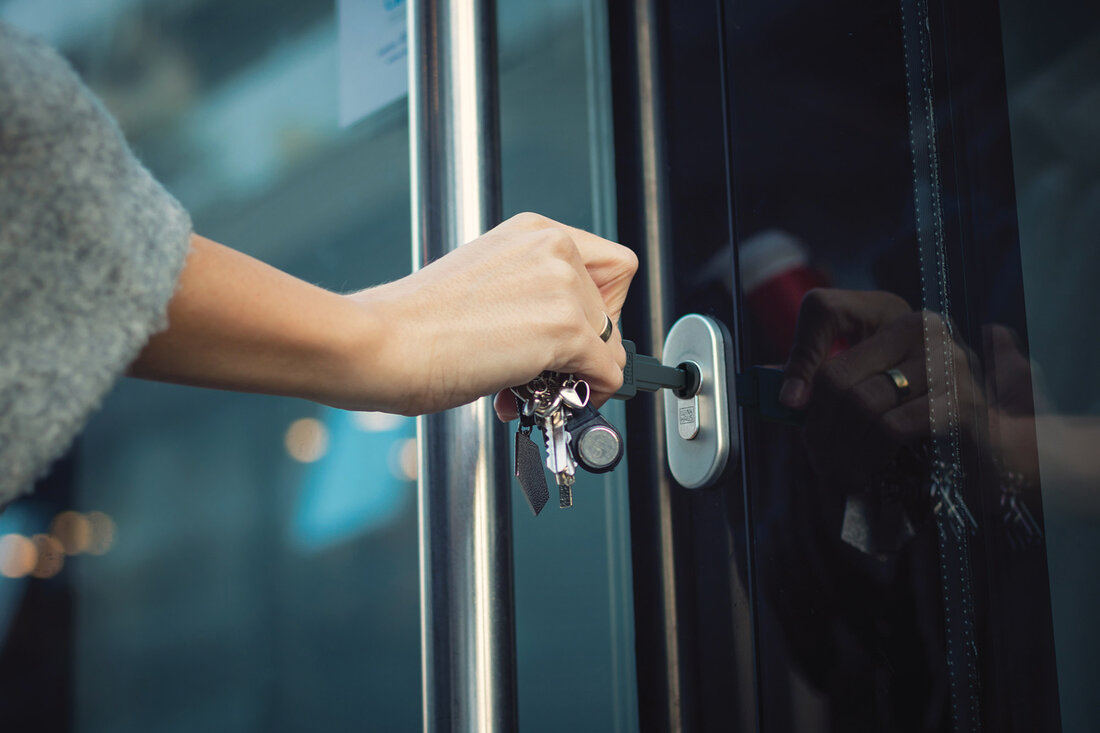 Hand mit Schlüssel sperrt Tür auf 