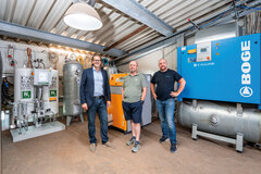 Schraubenkompressor mit drei Männern davor