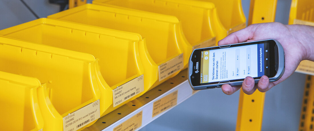 Scanner mit Web-App vor einem Regal 