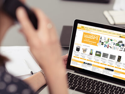 frau im bro schaut auf laptop und telefoniert Neuerungen im Webkatalog