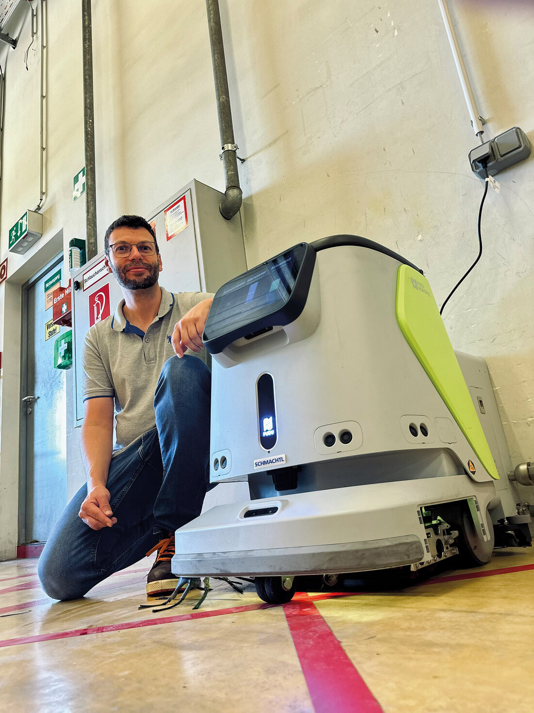 Mann kniet neben Wischroboter