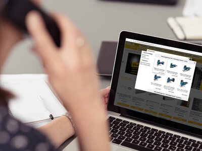 frau im bro schaut auf laptop und telefoniert webshopsuche