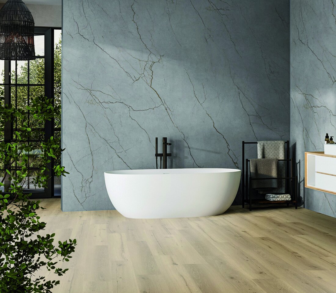 Badezimmer mit grauem Wandelement hinter einer freistehenden Badewanne