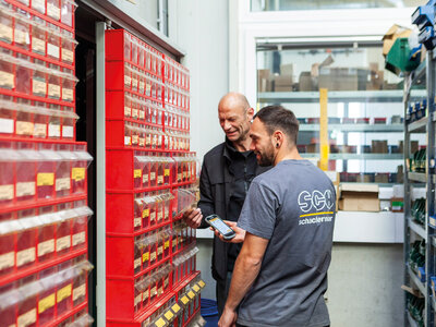 Kaeser C-Teile-Management Zwei Mitarbeiter scannen rote Schütten