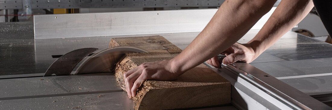 Hand mit Holzstück an Maschine