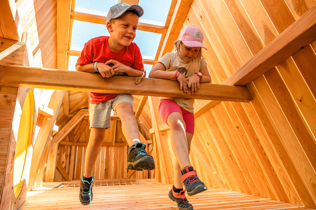 Spielende Kinder im Inneren eines Holzspielturms