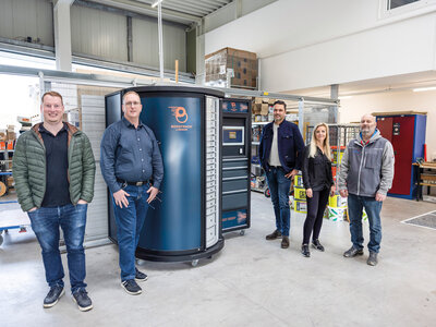 Fünf Menschen stehen rund um den BOOST.Tower, ein Beschaffungssystem