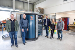 Fünf Menschen stehen rund um den BOOST.Tower, ein Beschaffungssystem