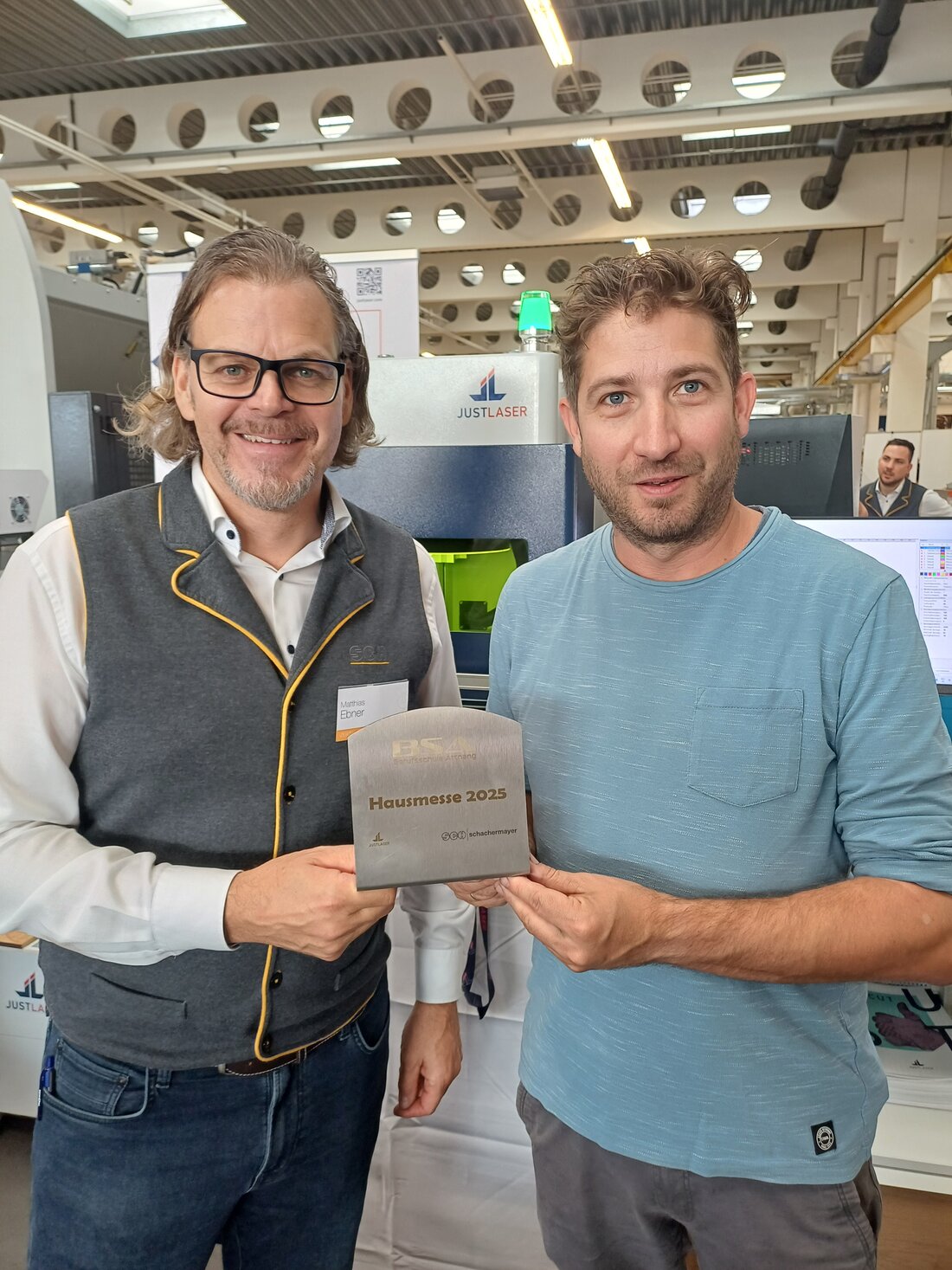 Zwei Männer halten eine Hausmesse-Plakette in die Kamera