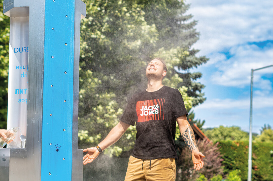 Mann genießt Sprühnebel von einem Trinkbrunnen