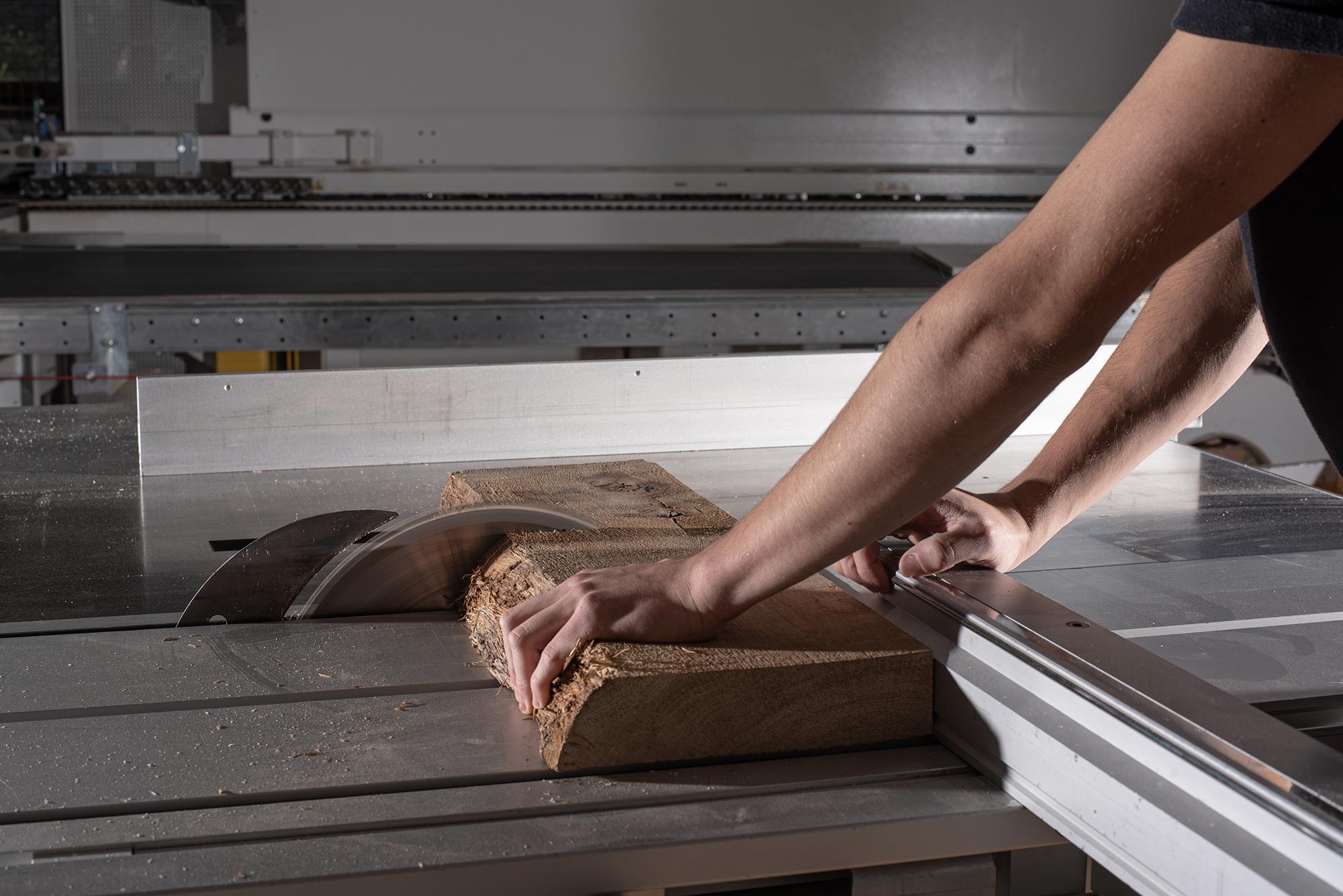 Hand mit Holzstück an Maschine